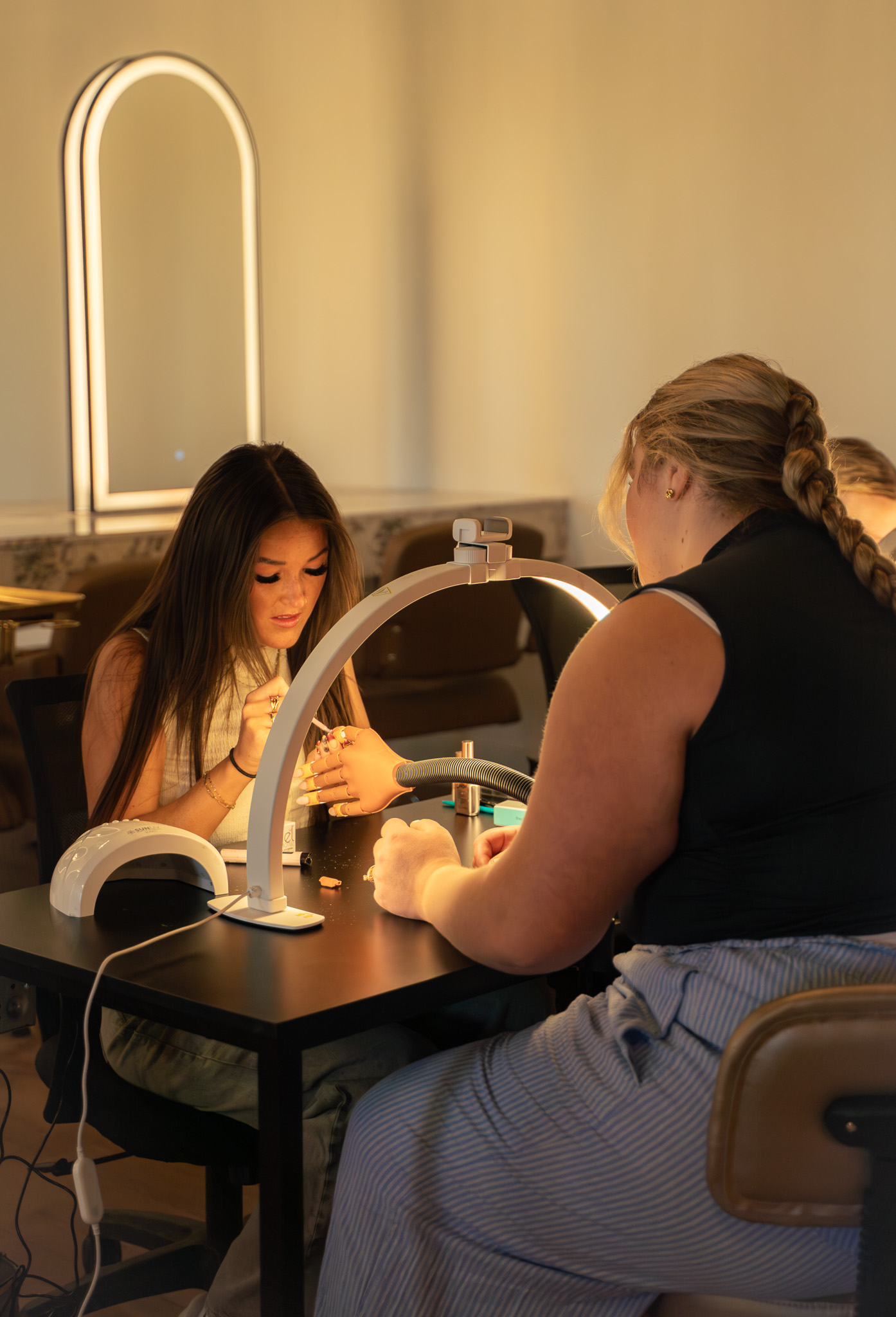 An instructor guiding hands-on nail training at Cambria Academy